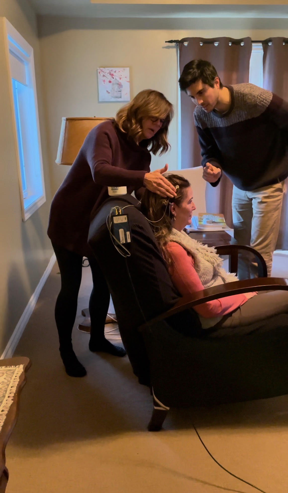 Practitioner and Jake placing neurofeedback sensors on a seated patient in a calm treatment room
